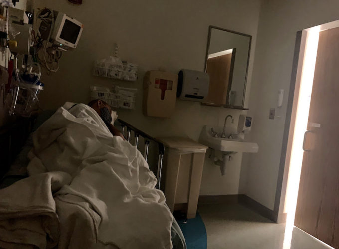 young woman laying down on hospital bed with door cracked open showing light